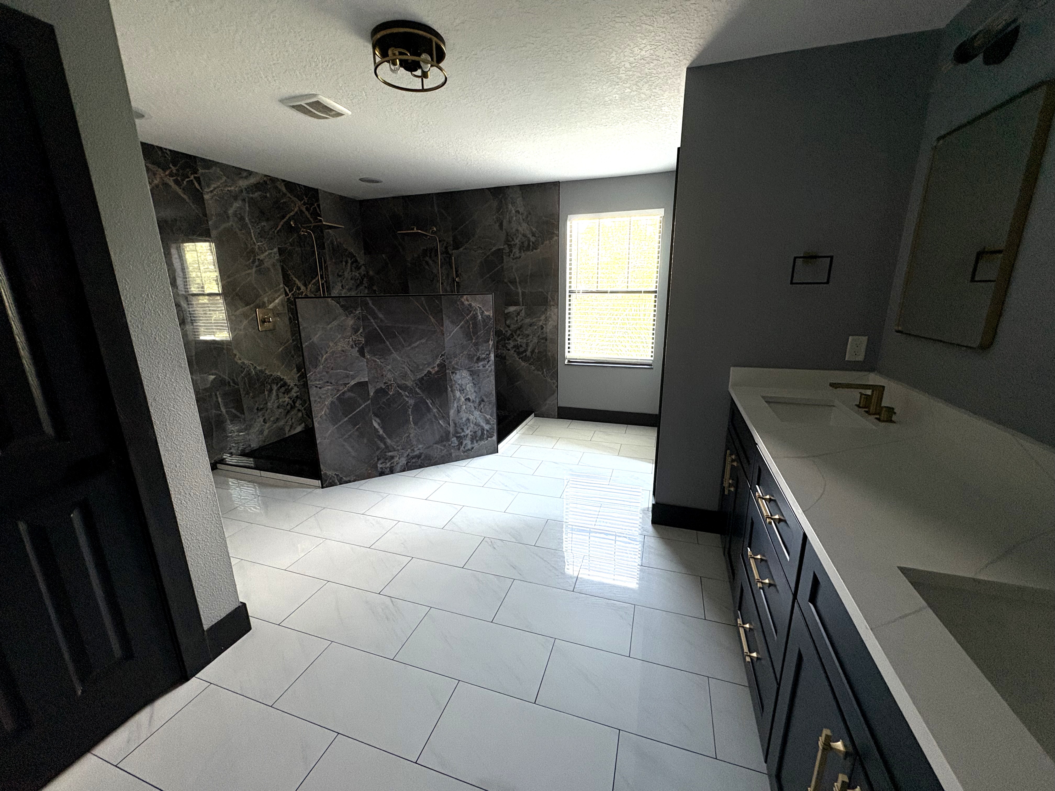 Dramatic dark marble walk-in shower with navy vanity and brass fixtures
